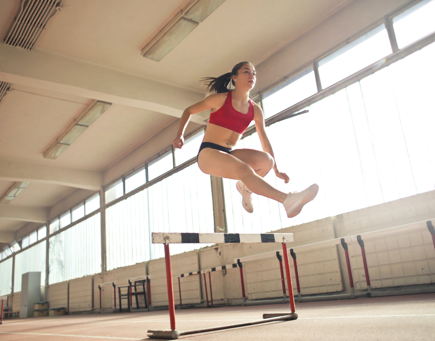 A woman jumping over a hurdle.